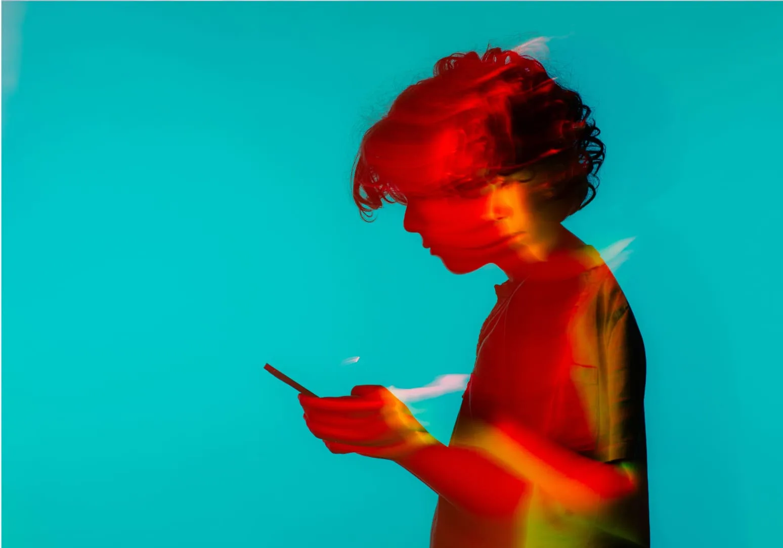 Person in profile looking at a phone, lit in red against a teal background